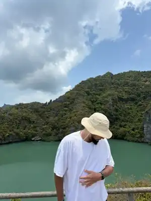 Edmond devant un lagon vert entouré de collines